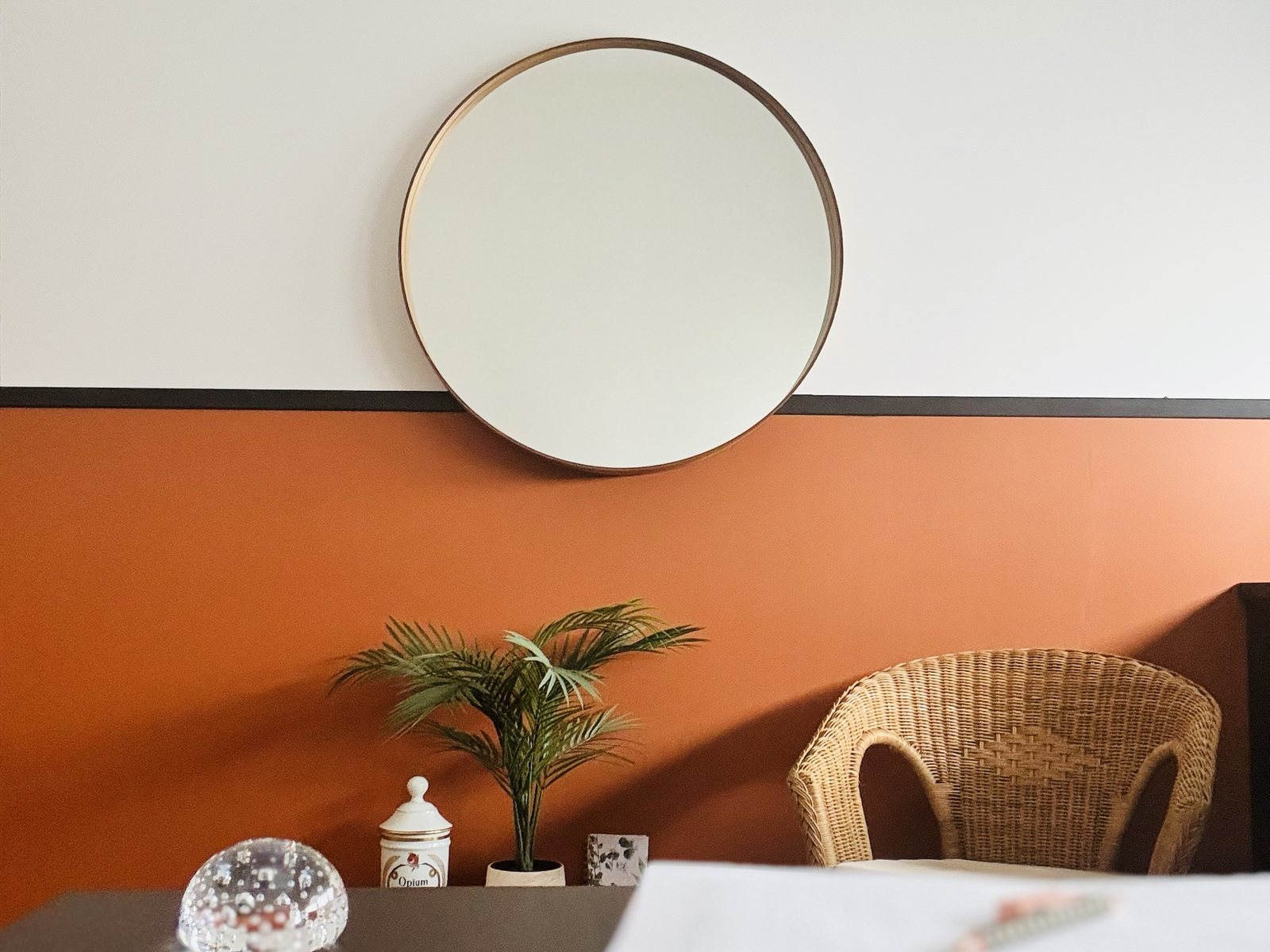 Bureau du cabinet de préparation mentale d'Annabelle Lauqué à Soustons : miroir rond, fauteuil en osier et mur terracotta